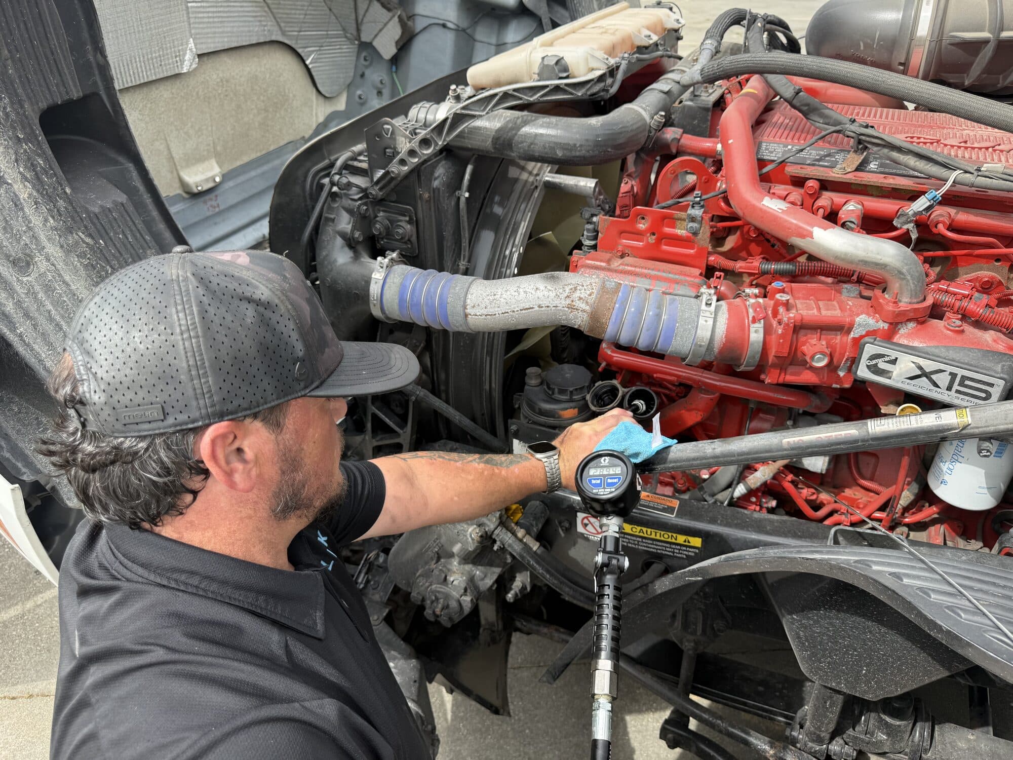 Slick heavy-duty technician metering fluid on a Class 8 engine during a PMI-B major service