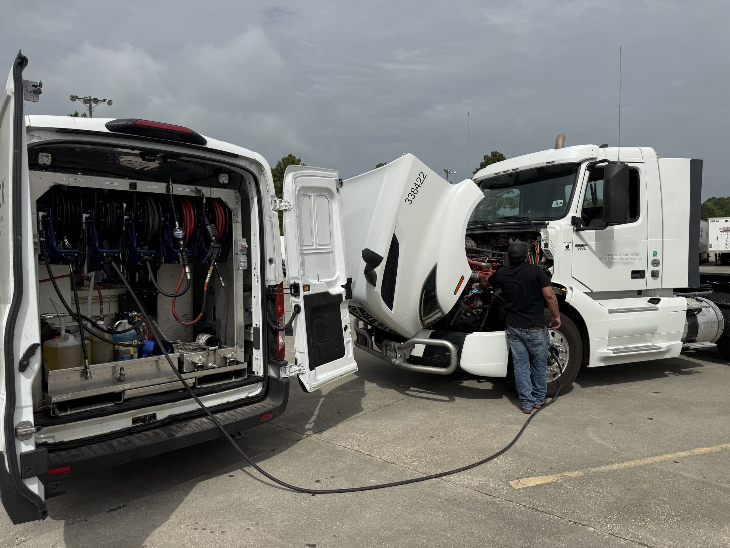 Slick heavy-duty technician servicing a Class 8 tractor on a customer yard during an HD PMI inspection